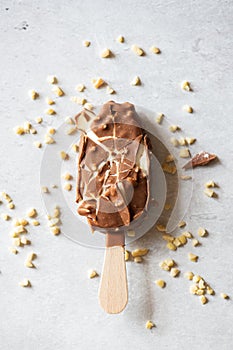 Cracked vanilla almond ice cream with chocolate glaze on a wooden stick on a gray background. Top view