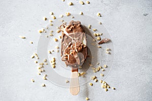 Cracked vanilla almond ice cream with chocolate glaze on a wooden stick on a gray background. Top view