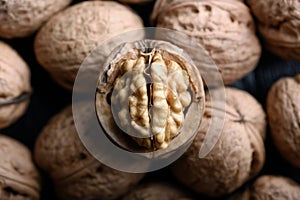 Cracked walnut with kernels on heap of whole walnuts