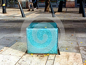 Cracked white blue glass cube seat on public street of laminated tempered safety glass