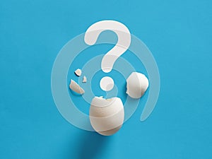 Cracked white chicken egg shell with question mark symbol. Surprise, mystery, uncertainty or baby gender prediction