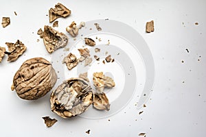 Cracked and whole walnuts on a white background, with a scattered shallow shell, in natural light from the window