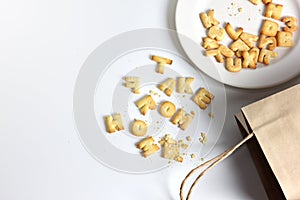 Cracker or Cookie ABC letter alphabet in white dish with copy space on white background pile on the floor
