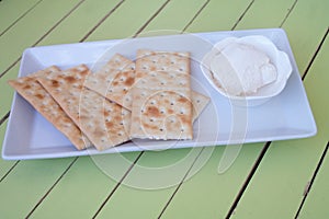 Crackers and spreadable cheese on green wood