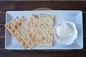 Crackers and spreadable cheese on wood from above
