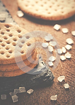 Crackers stack together on black stone, coarse sugar on wooden b