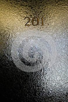 Crackled glass in office door window with numbers and dim lighting