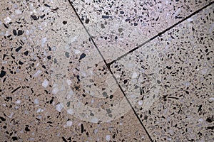 Cracks in the concrete floor with granite chips. Large differently colored floor tiles separated by thin lines