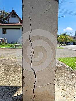 Cracks in damaged building pillars. Cracked concrete pillar of an old house. Deep and clear fractures, on the front surface of an