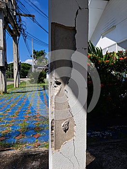 Cracks in damaged building pillars. Cracked concrete pillar of an old house. Deep and clear fractures, on the front surface of an