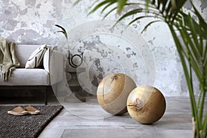 Craetive compostion of indiustral living room interior with design gray sofa, wooden ball, modern coffee table, gray concrete photo