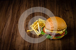Craft beef burger with cheese, rocket leafs and french fries on wood table and rustic background