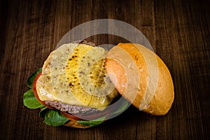 Craft beef burger with cheese and rocket leafs on wood table and rustic background