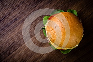 Craft beef burger with cheese and rocket leafs on wood table and rustic background