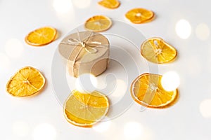 Craft box and dried oranges on a white background with christmas lights and copy space. Healthy sweets concept. Flat lay