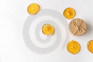 Craft box and dried oranges on a white background with christmas lights and copy space. Healthy sweets concept. Flat lay