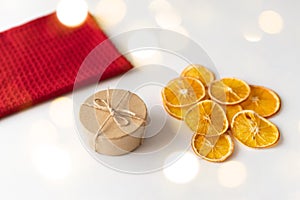 Craft box and dried oranges on a white and red background with christmas lights and copy space. Healthy sweets concept. Flat lay