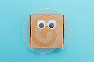 Craft box with eyes. Box for moving. Square Emoji made of paper. Funny paper cubes with eyes.