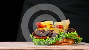 Craft burger is cooking. Consist: red sauce salsa, lettuce, red onion, pickle, cheese, chilli green pepper, air bun and