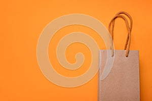 Craft cardboard gift bag on orange background