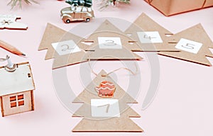 Craft Christmas trees with numbers from 1 to 5 with a wooden house and a toy car with a Christmas tree on a pink.