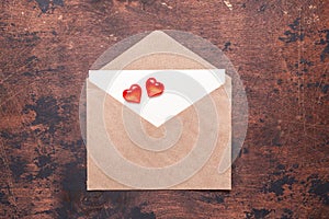 Craft envelope with red hearts on a vintage wooden background Piece of paper Valentine day concept Flat lay