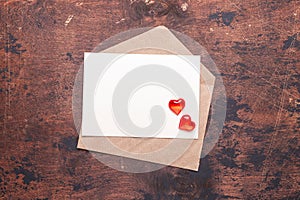 Craft envelope with red hearts on a vintage wooden background Piece of paper Valentine day concept Flat lay