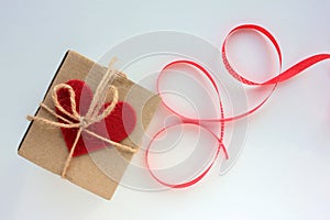 Craft gift box with red fabric hearts and red ribbon on white background. Happy Valentine`s day concept.