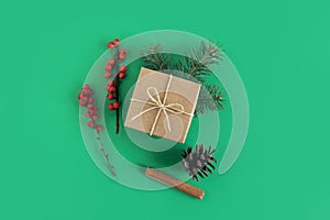 Craft gift box with spruce branches, cinnamon sticks and pine cone on a green background