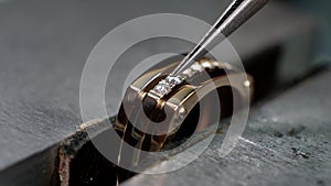 Craft jewelery making. Goldsmith putting the diamond on the ring. Macro shot.