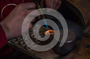 Craft jewelery making with professional tools. Macro shot. A handmade jeweler process, manufacture of jewellery. Melting metal