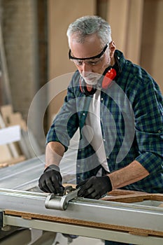 Craft man in plaid shirt working in a carpenter workshop