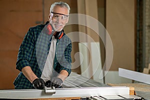 Craft man in plaid shirt working in a carpenter workshop