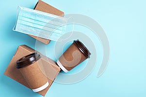 Craft paper cups with coffee to go and food box, lunch on blue background. Top view. Banner, copy space. Safe delivery, take away