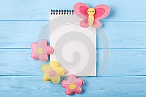 Craft pink and yellow butterfly and flowers with white paper, copyspace on blue wooden background. Hand made felt toys. Abstract s