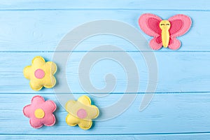 Craft pink and yellow butterfly and flowers with white paper, copyspace on blue wooden background. Hand made felt toys. Abstract s