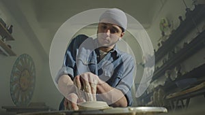 A craft potter makes a product from clay on a potter's wheel.