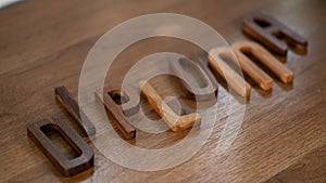 Crafted Elegance: Walnut 3D Letters Spell \'Diploma\' on Wooden Table