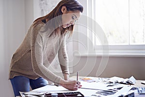 Crafting the perfect portfolio. A young woman working on her portfolio at home.