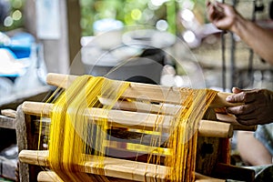 Crafts and craftsmanship. Silk raising for silk threads. yarn warping machine in a textile weaving crafsmanship. Hand of woman
