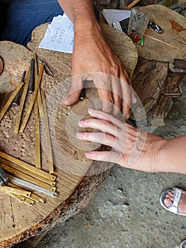 A craftsman from the ancient center for the handicraft production of copper utensils Lahich makes a personal amulet for tourists,