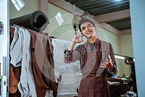 craftsman in apron making phone calls at leather workshop