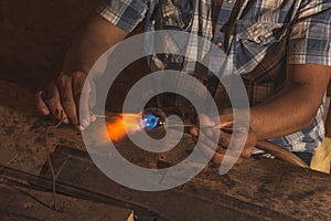 Craftsman blowing glass to create Christmas balls in his workshop