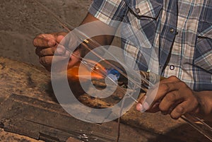 Craftsman blowing glass to create Christmas balls in his workshop