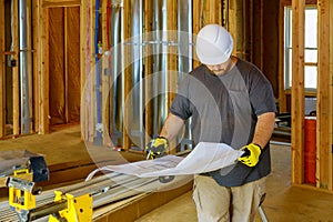 Craftsman, building checking a plan on a construction of house under construction