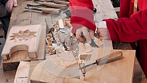 A craftsman carved a baking dish gingerbread and cookies out of wood with a knife. Art wood carver makes wood carvings