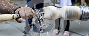 A craftsman carves a piece of wood with a lathe