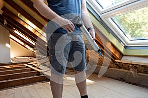 Craftsman caulking a new window in the attic.