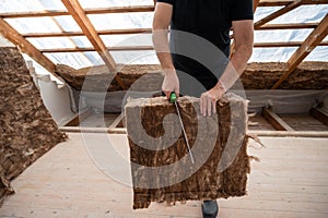 Craftsman cutting insulation material to insulate the attic