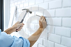 Craftsman doing renovation work at home improvement with using hammer to driving nail on brick wall and interior design concept